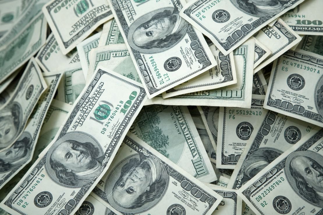 A photo of various $100 US Dollar bills on a table